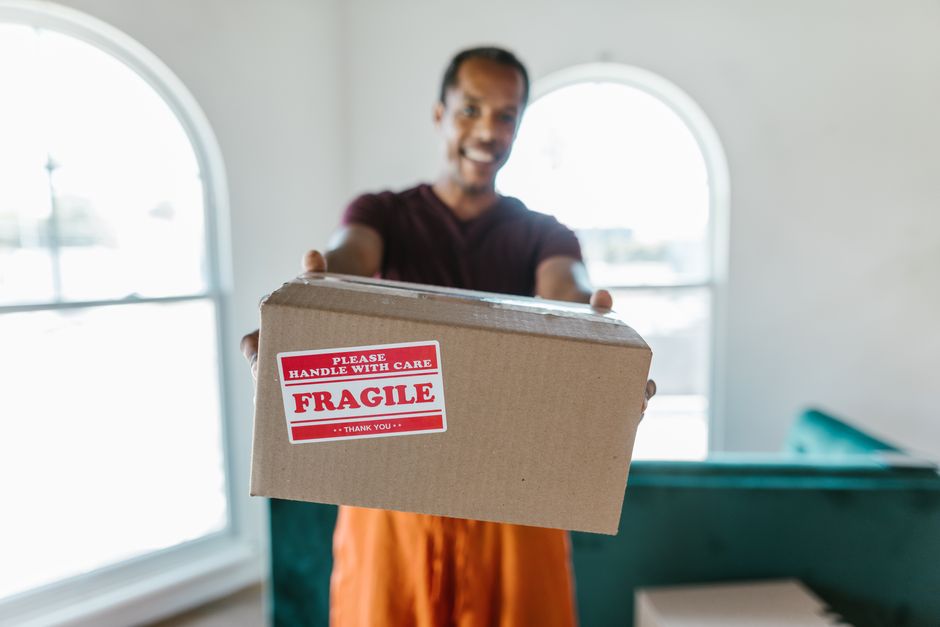 Smiling mover holding a securely taped moving box